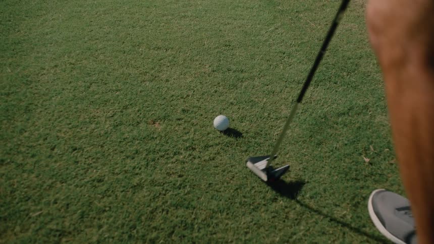 Player positioning the golf ball on the grass field