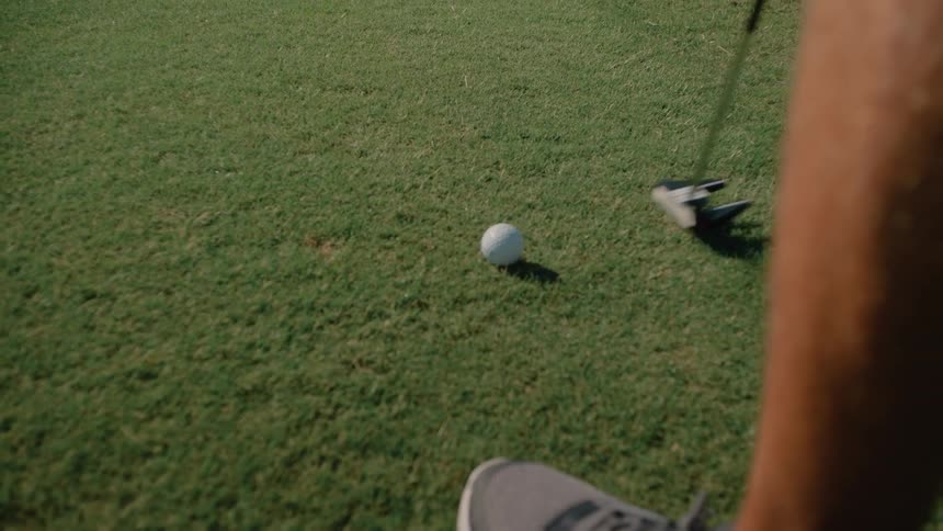 Golf ball positioned in front of the putter on the grass during shot preparation