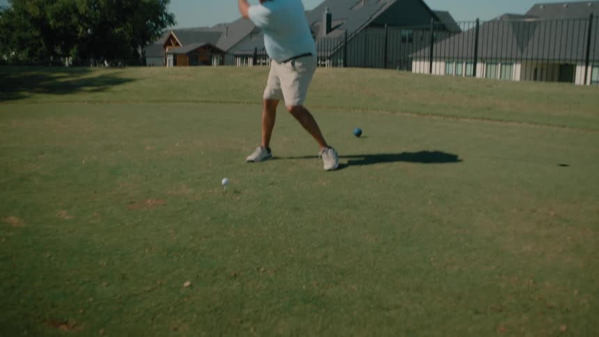 Man stands holding his golf club near the ball then swings and hits the ball