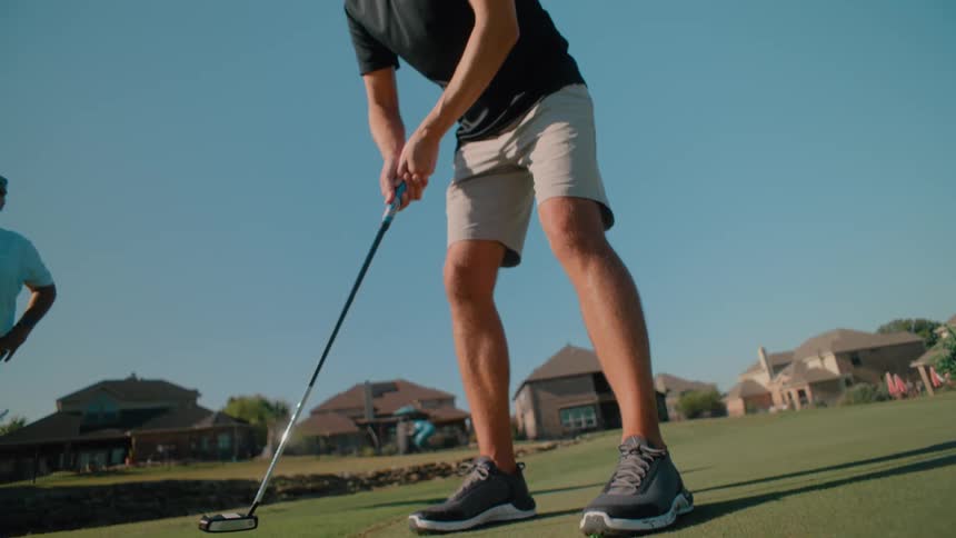 Golfer takes a light swing on an outdoor course during the day