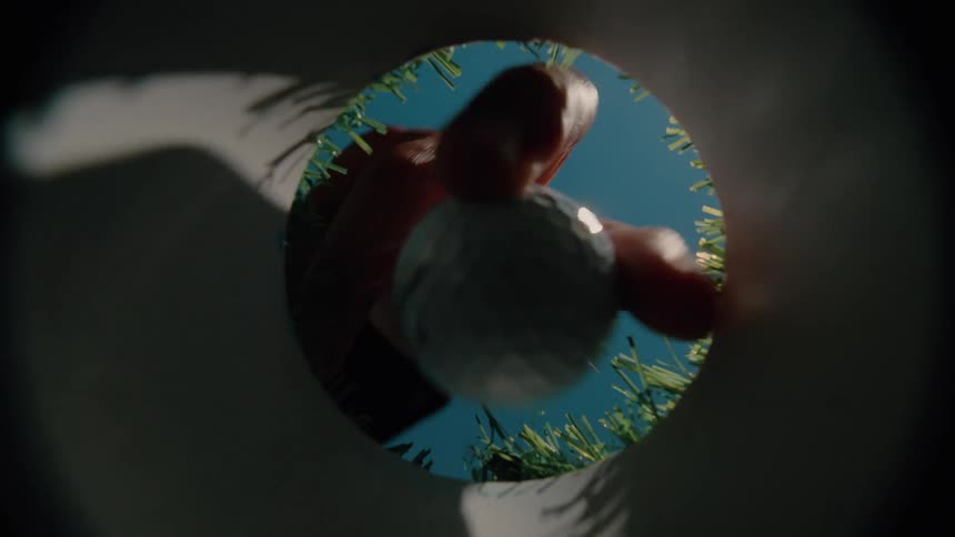 Hand picks up a golf ball from a target