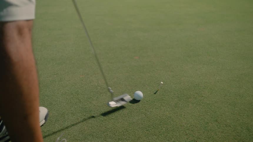 Putter aligns the ball on the green between the players feet before the stroke