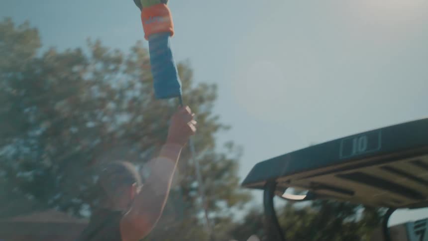 Man in cap picking up golf equipment