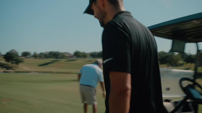 Golfer picks up a club and positions himself near the ball