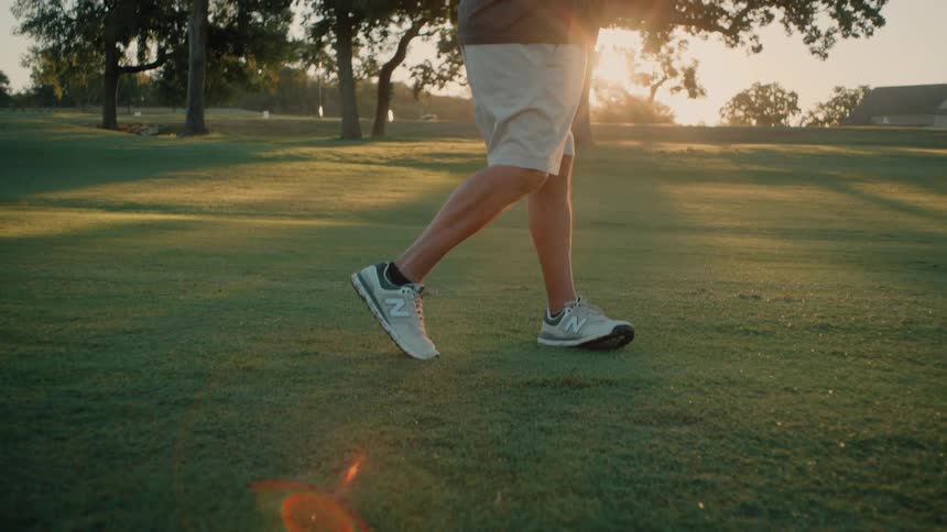 Golfer executes a shot on the fairway with the ball positioned in front of the feet