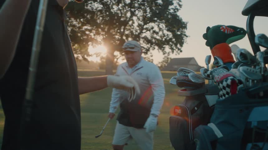 Two people putting away golf clubs