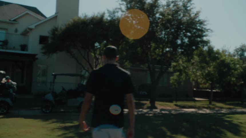 Male golf player sticking a flag on a hole and then walking towards another man next to golf carts outdoors during day time