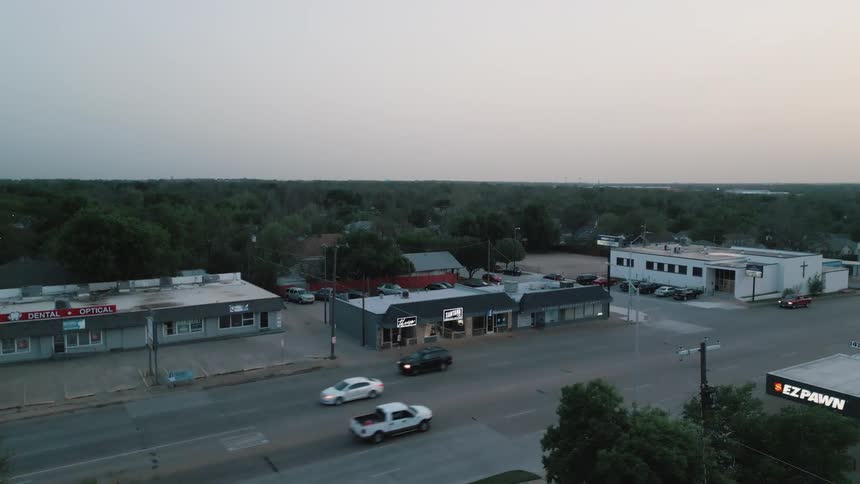 Cars drive past the stores in town