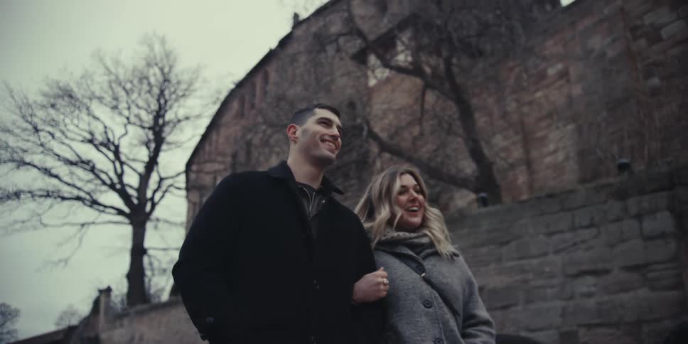 Couple walks together along a historic street beside a stone wall