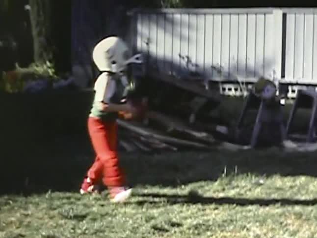 Young boys wearing football helmets while playing catch in a backyard