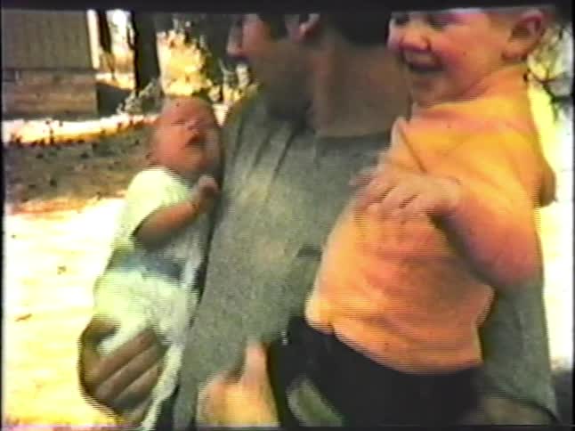 A father happily holds his infant and young son