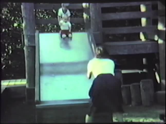 Mother and son sliding down a slide in a playground