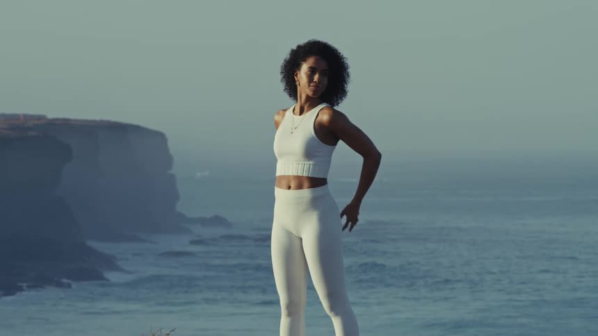Woman stretches while working out on a seaside cliff on a foggy day