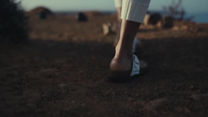 Sandaled steps move along a dirt path in a natural environment