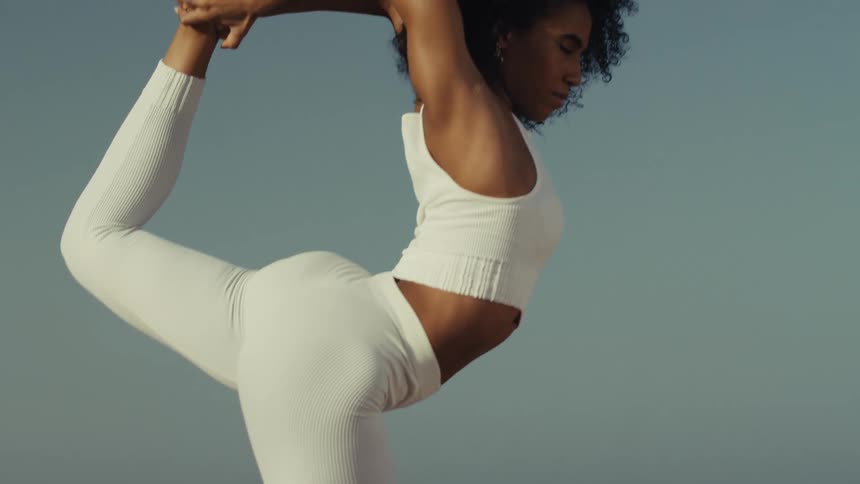 A focused woman gracefully holds a challenging yoga pose her body a picture of strength and balance against the vast serene ocean