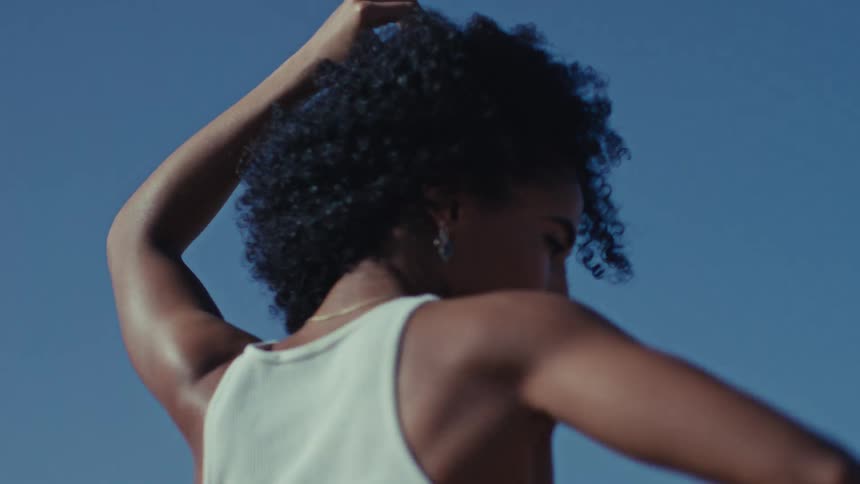 Woman standing on a yoga mat on a seaside cliff dances on a summer day