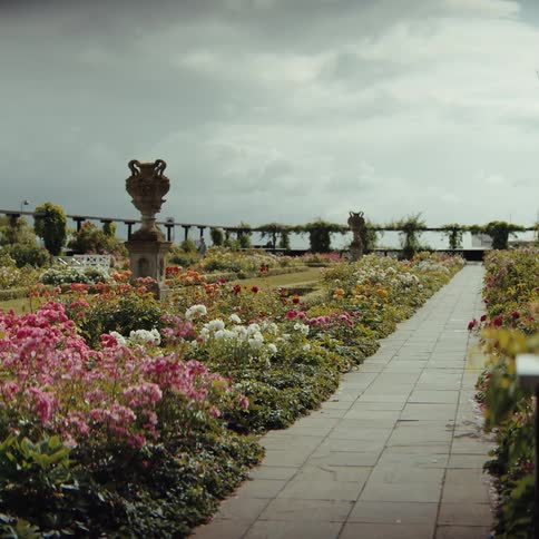 Formal garden with flower beds and a stone path under a cloudy sky