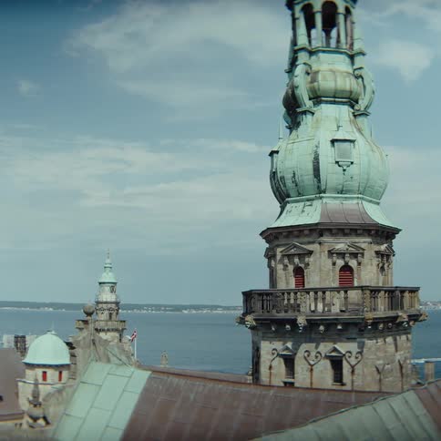 Historic tower with a copper dome above coastal buildings and the sea in the background