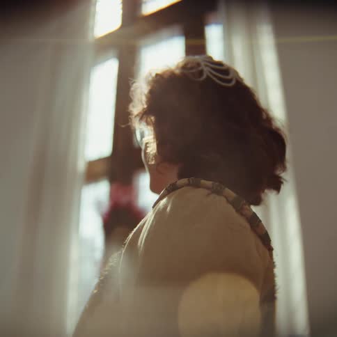 The woman is fanning her face by the window