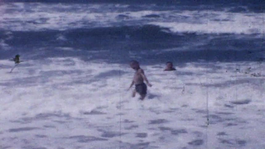Two children play and wade in the ocean waves on a sunny beach on a sunny day