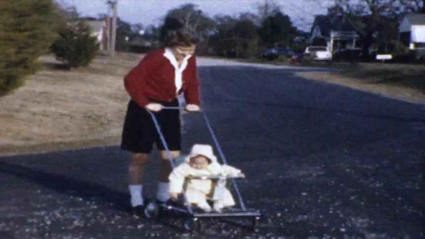 Mother pushing her baby in a carriage on the road