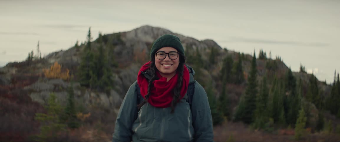 A portrait of a woman standing in mountainous terrain and smiling