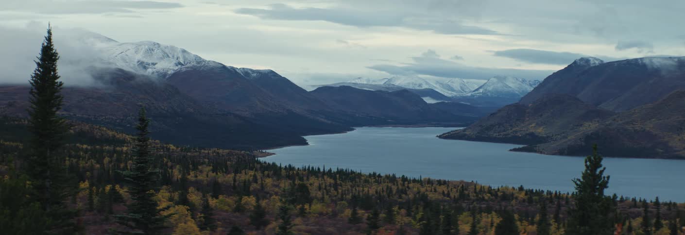 The video features a vast cinematic landscape with autumn trees, large lake and tall snow-capped mountains