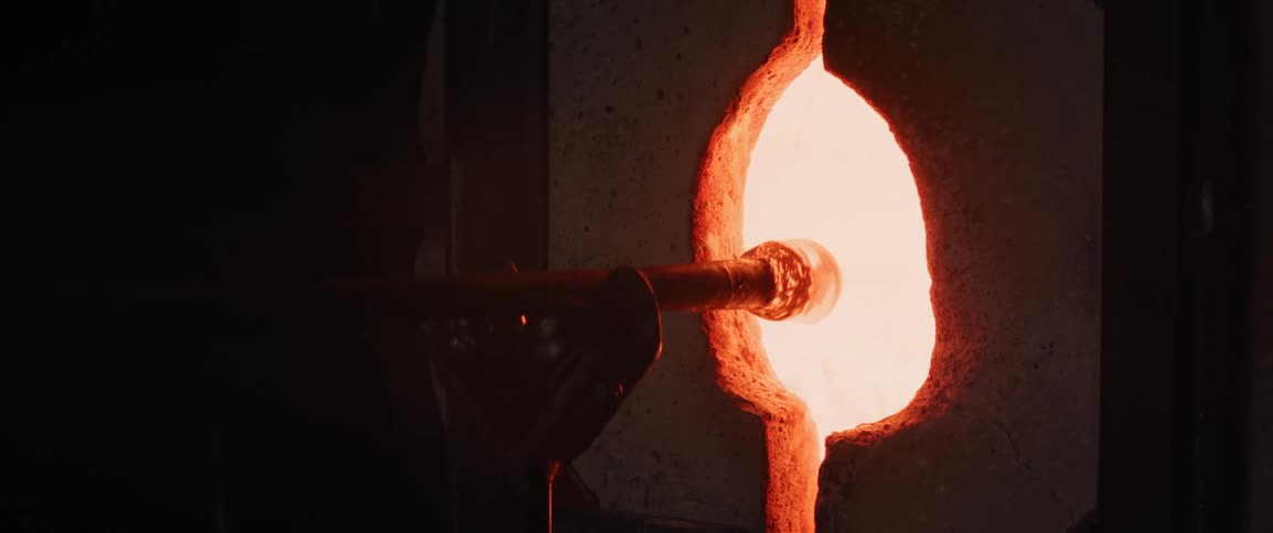 A glassblowing rod is removed from the red hot glory hole furnace