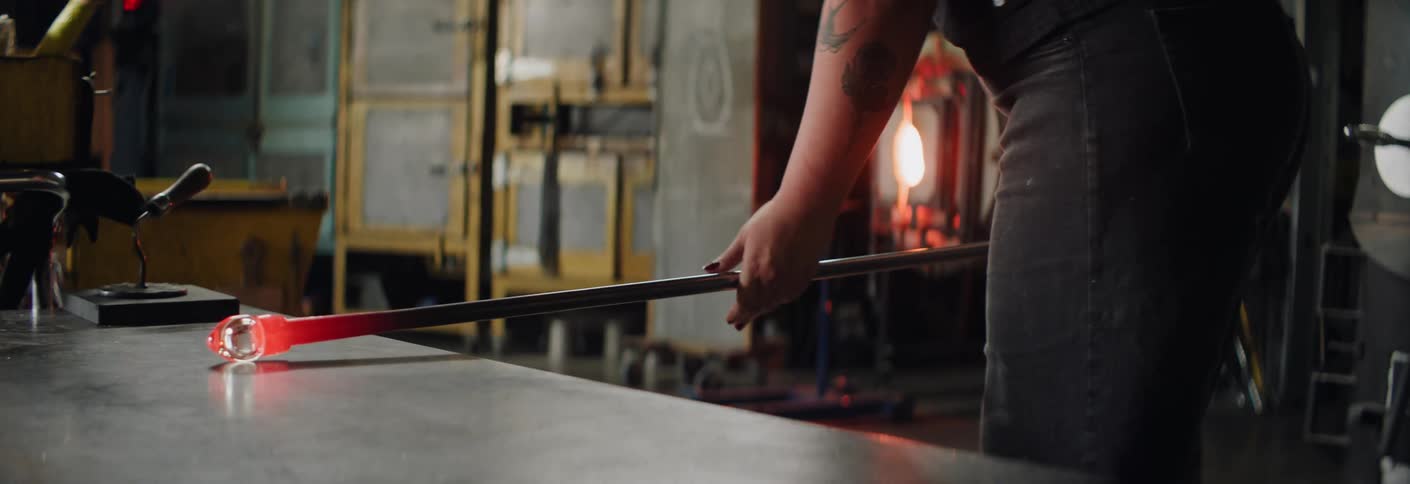 Molten glass being shaped on a metal table in a glassblowing workshop