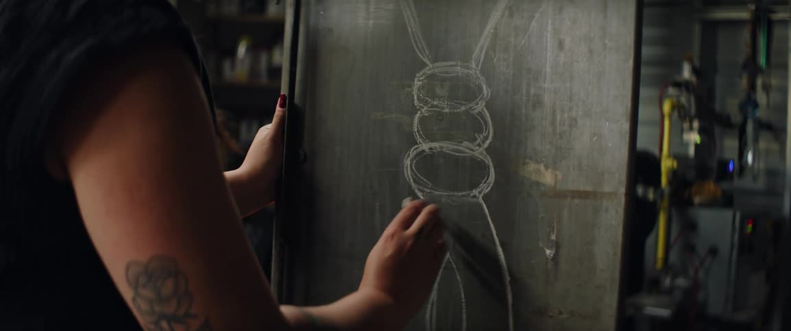 A woman draws on a chalk board to plan her design