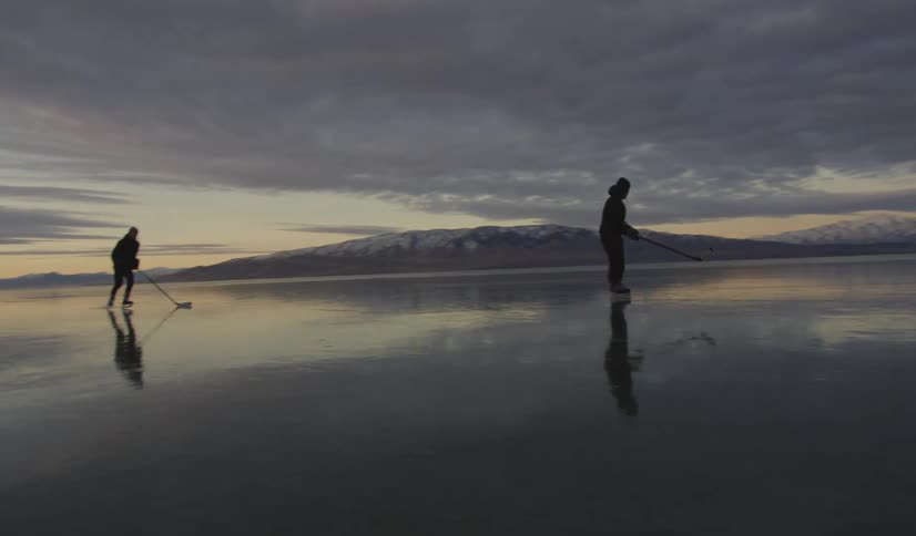 Two people play hockey on the frozen lake