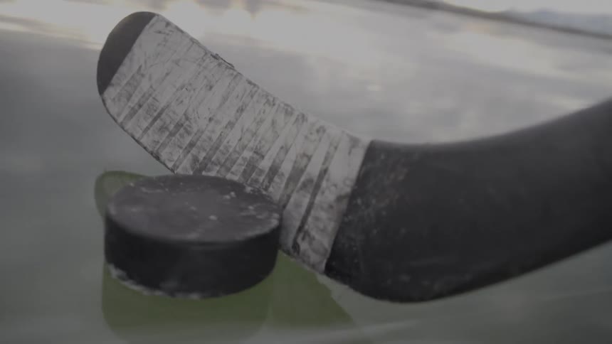 A close up of a hockey stick hitting a puck