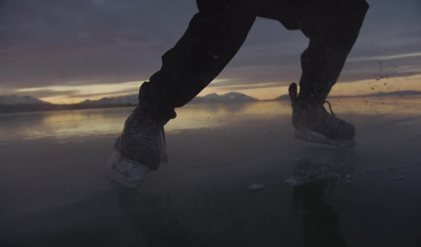 Person ice skating with mountains in the background during sunset