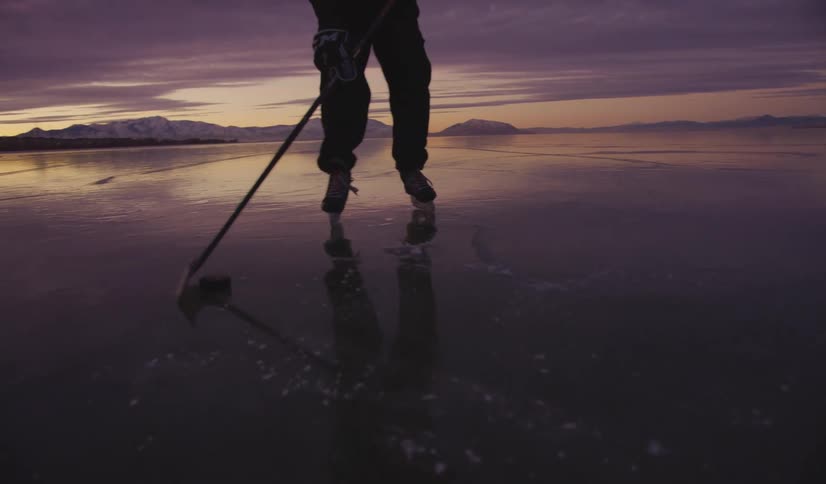 Person controls a hockey puck on a frozen lake at dusk