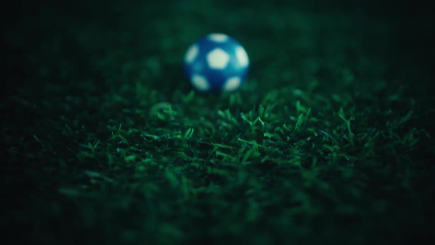 Blue and white soccer ball placed on dark grass