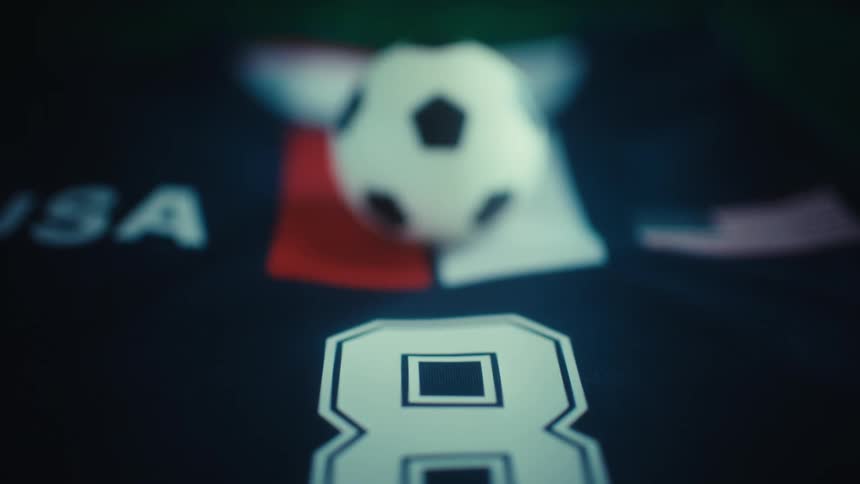 A shallowfocus shot highlights the number eight on a soccer jersey with a soccer ball and national flag blurred in the background