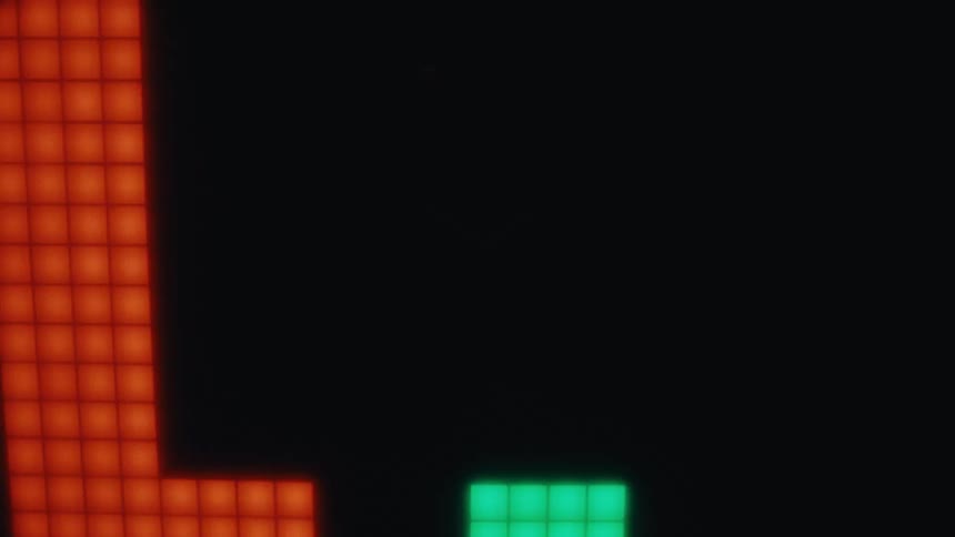 Green and orange pixelated shapes on black background