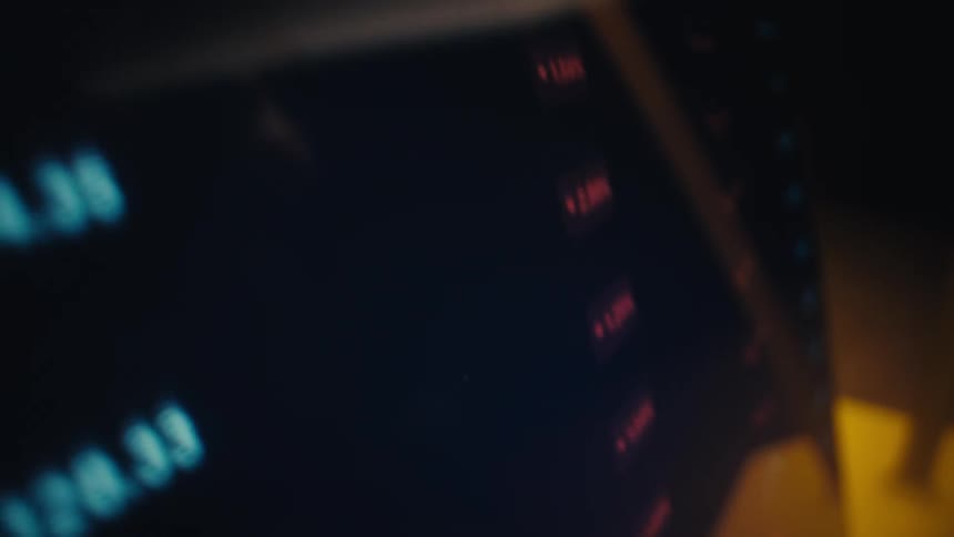 A stylus pen points to and scrolls through various financial figures cryptocurrency market caps for usdt and xrp and fluctuating line graphs displayed on a dark digital screen in a dimly lit room