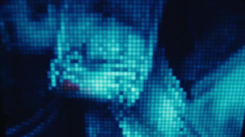 A closeup of a digital screen shows glowing blue pixels forming abstract images of dollar bills