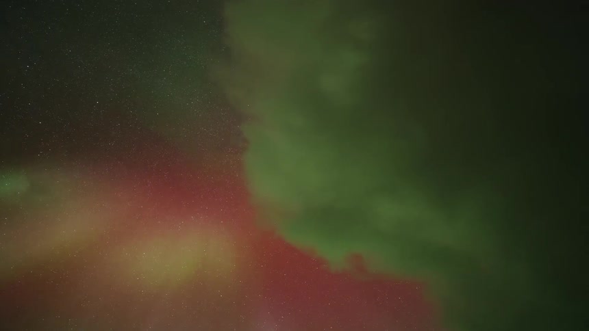 Colorful glowing lights of the aurora borealis move across a starry sky
