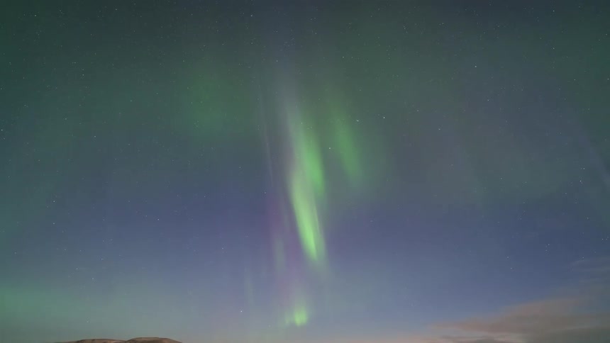 Aurora borealis over an open plain with low vegetation and distant hills at night