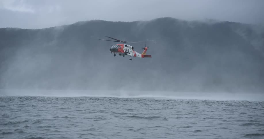 Helicopter hovering over water off the mountain coast