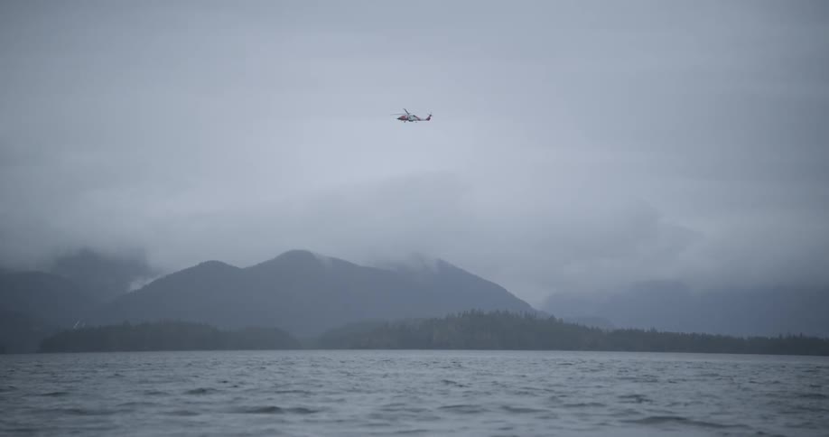 The helicopter flies over the foggy mountain