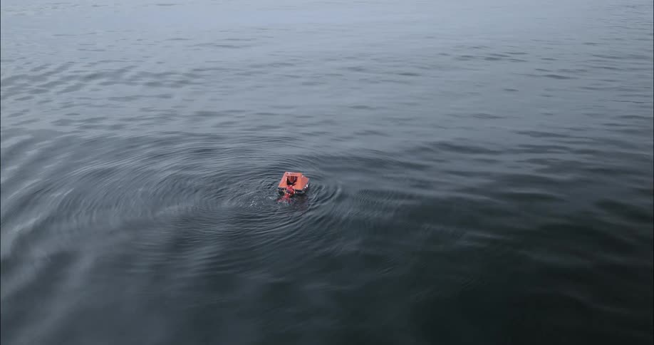 The man swims to and then climbs into the small rescue life raft on the ocean