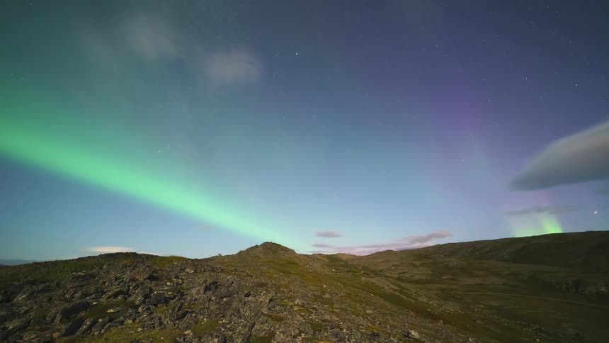 The aurora borealis glows green over the landscape