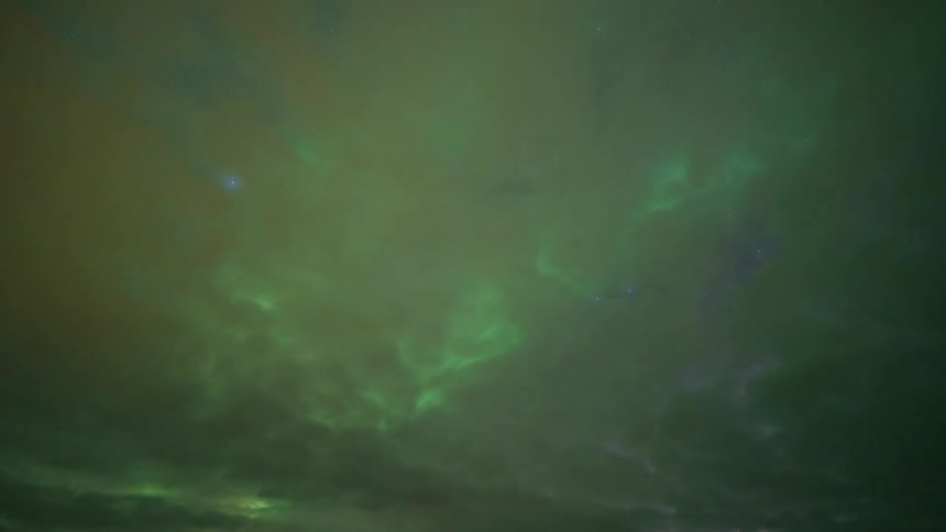 A cloudy day with heavy dark clouds covering the sky and a green light glowing underneath them casting an eerie illumination across the scene