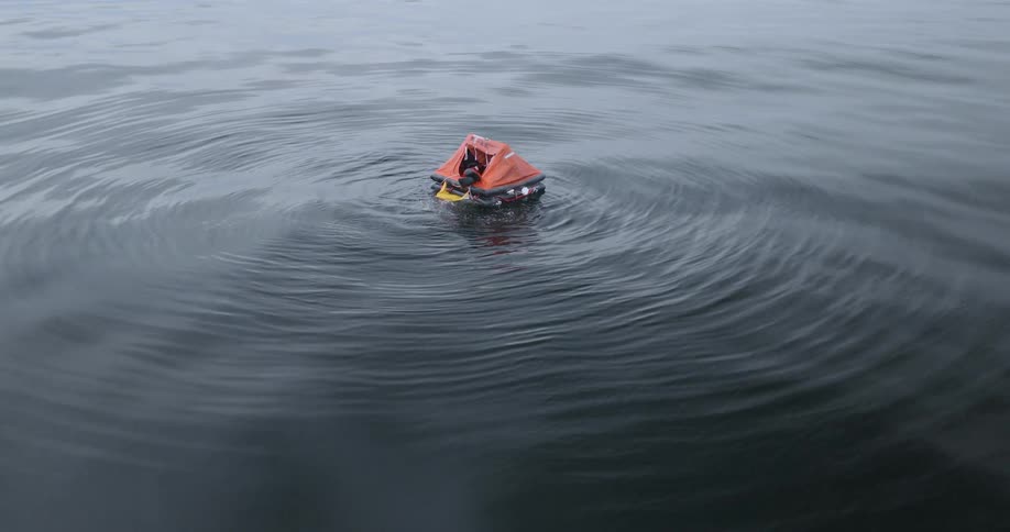 The person is being rescued in a life raft on the ocean
