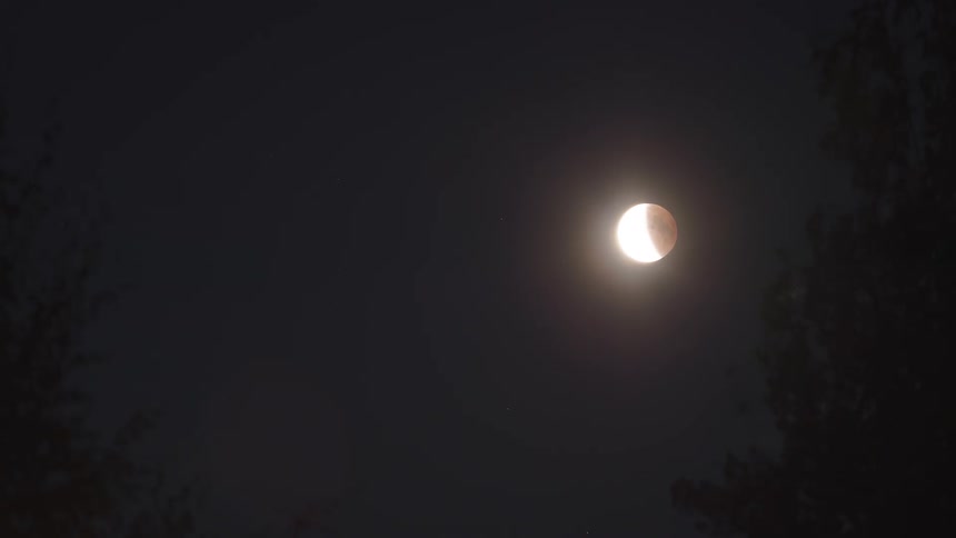 The full moon hangs in the night sky slowly shifting its position as the earth rotates beneath it