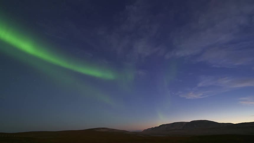 The green aurora spins and waves over the landscape