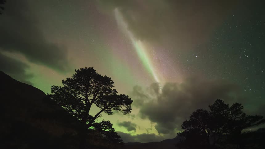 The thick clouds mix with the northern lights in the sky
